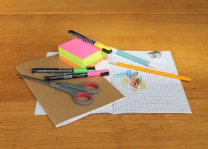 Allocation de rentrée scolaire en 2026 (ARS): découvrez les plafonds, montants, et les nouvelles règles de la CAF en 2026 (guide complet) Fournitures scolaires diverses (cahier, ciseaux, stylos) posées sur un bureau, illustrant le budget de la rentrée et l'utilisation de l'Allocation de Rentrée Scolaire (ARS) 2026.