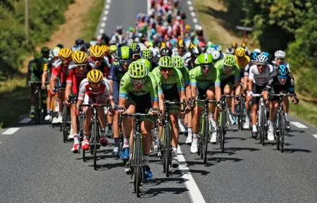 Pourquoi la radio en cyclisme reste un sujet explosif malgré 20 ans d’usage dans le peloton Peloton de coureurs cyclistes professionnels en pleine course sur route, illustrant la communication radio entre équipes et directeurs sportifs