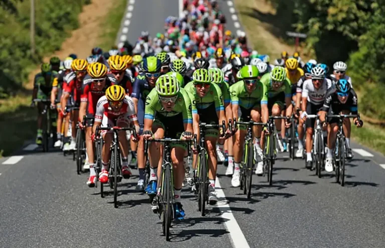 Peloton de coureurs cyclistes professionnels en pleine course sur route, illustrant la communication radio entre équipes et directeurs sportifs